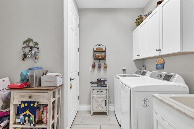 clothes washing area with light tile patterned floors, baseboards, cabinet space, and washer and clothes dryer