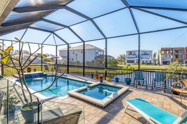 view of swimming pool featuring a water view, a pool with connected hot tub, glass enclosure, a residential view, and a patio area