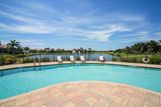 pool featuring a patio, fence, and a water view