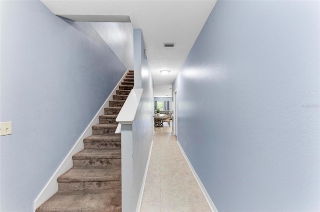 stairs with tile patterned floors, visible vents, and baseboards