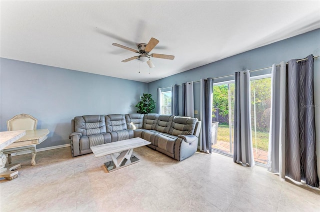 living area with ceiling fan, a textured ceiling, and baseboards