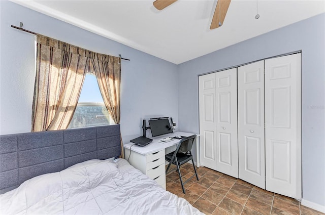 bedroom with a closet, ceiling fan, and stone finish flooring