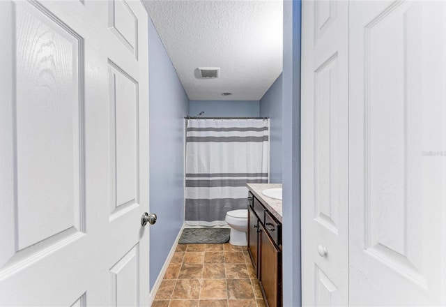 full bathroom featuring a textured ceiling, curtained shower, toilet, vanity, and baseboards