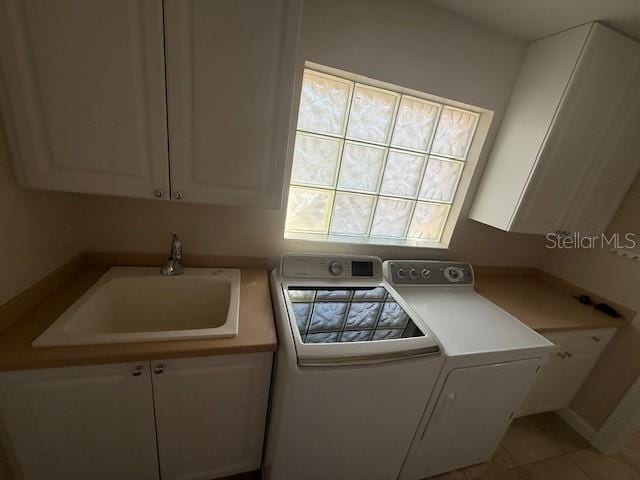 clothes washing area with cabinets, washing machine and clothes dryer, light tile patterned flooring, and sink