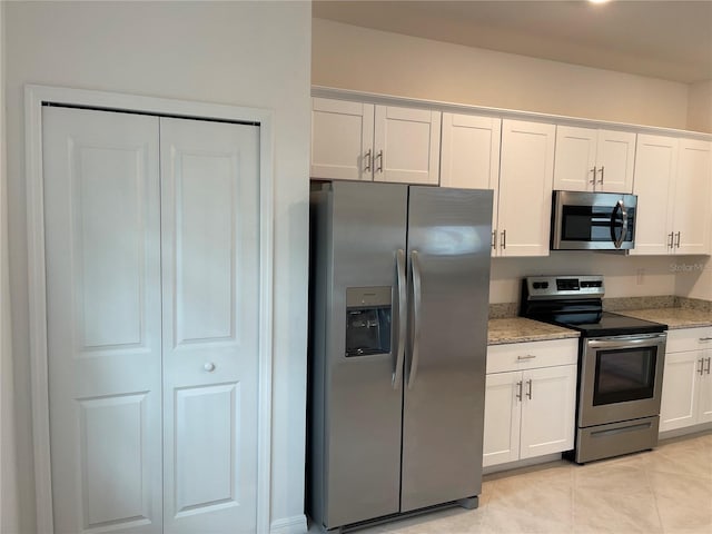 kitchen featuring white cabinetry, appliances with stainless steel finishes, light stone countertops, and light tile patterned floors