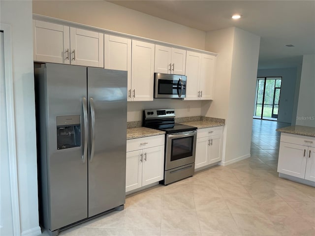 kitchen featuring light tile patterned flooring, appliances with stainless steel finishes, light stone countertops, and white cabinets