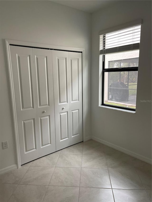 unfurnished bedroom with light tile patterned floors and a closet