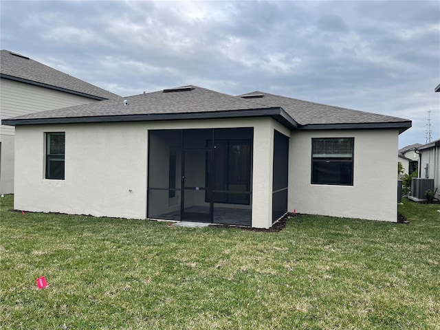 back of house featuring a sunroom, central AC unit, and a lawn