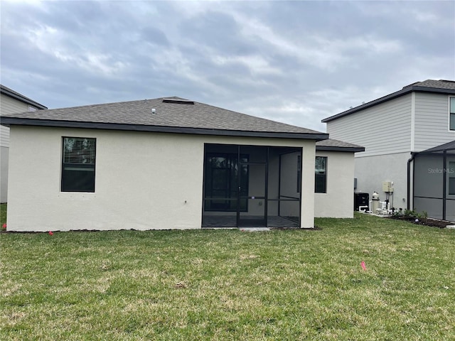 rear view of house featuring a yard and a sunroom