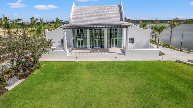 back of property featuring a water view and a lawn