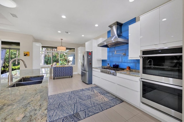 kitchen with white cabinets, wall chimney exhaust hood, modern cabinets, stainless steel appliances, and a sink