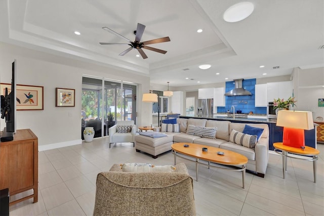 living area with light tile patterned floors, baseboards, and a raised ceiling