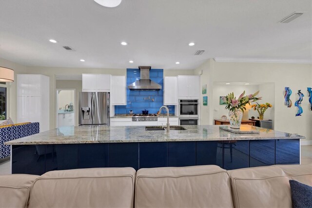 3301 River Woods Dr, Parrish, FL 34219 - kitchen with stainless steel appliances, wall chimney range hood, white cabinetry, a sink, and modern cabinets
