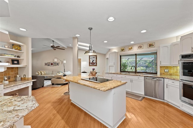 kitchen with appliances with stainless steel finishes, white cabinets, decorative light fixtures, vaulted ceiling, and light wood-type flooring