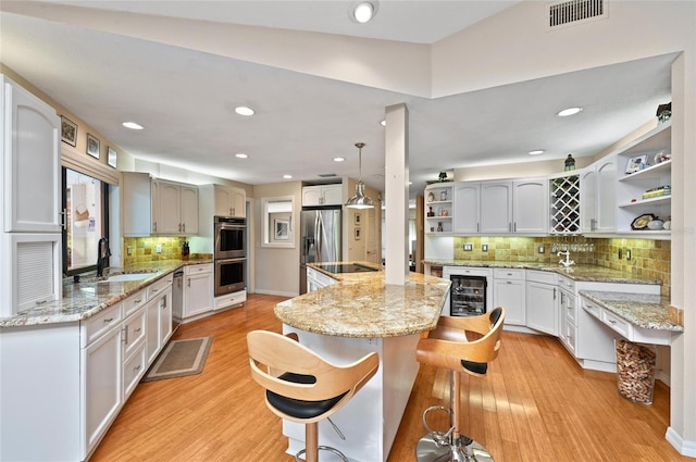 kitchen featuring appliances with stainless steel finishes, sink, white cabinets, hanging light fixtures, and a center island