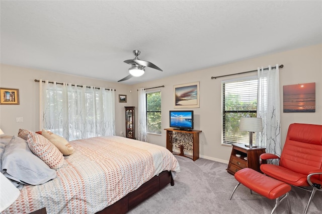 bedroom featuring ceiling fan, light colored carpet, and multiple windows