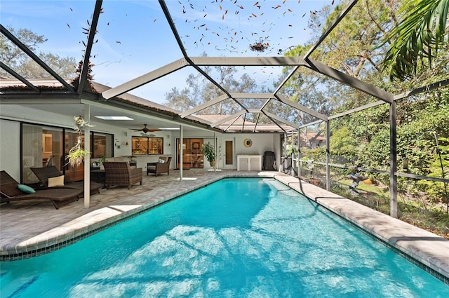 view of swimming pool featuring ceiling fan, an outdoor hangout area, a patio area, and glass enclosure