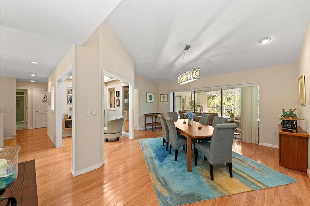 dining space featuring a chandelier, baseboards, vaulted ceiling, and light wood-type flooring