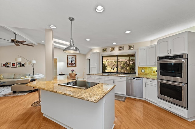 kitchen featuring a sink, appliances with stainless steel finishes, vaulted ceiling with beams, and light wood-type flooring