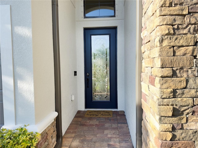 entrance to property featuring stone siding and stucco siding