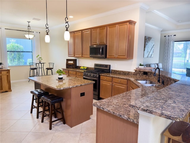 kitchen featuring appliances with stainless steel finishes, a breakfast bar, dark stone countertops, ornamental molding, and a sink