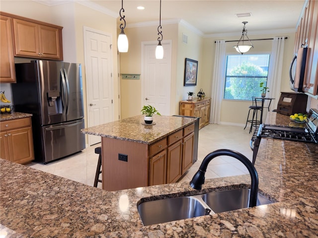 kitchen with a sink, appliances with stainless steel finishes, brown cabinetry, dark stone countertops, and crown molding