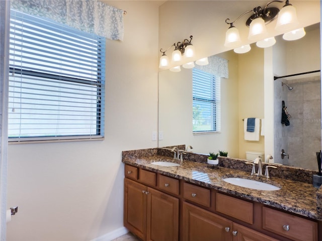 full bathroom featuring toilet, double vanity, walk in shower, and a sink