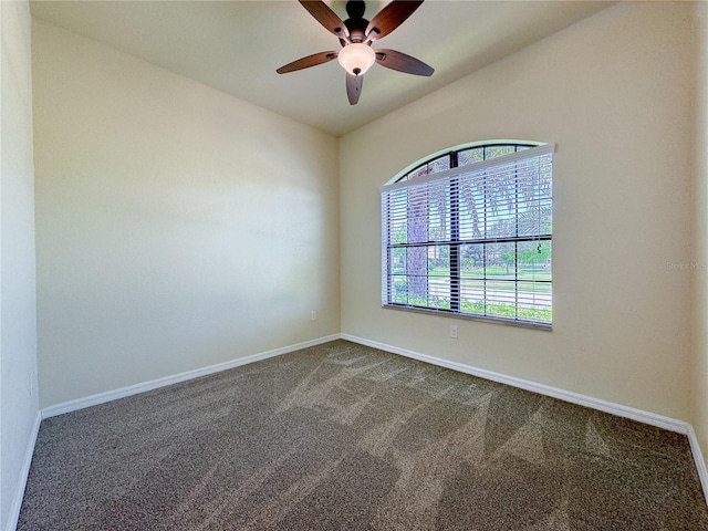 unfurnished room with lofted ceiling, dark colored carpet, a ceiling fan, and baseboards