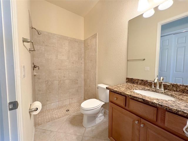 full bath with toilet, tile patterned flooring, tiled shower, and vanity