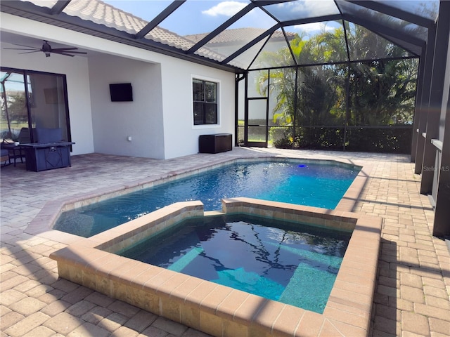 view of pool with a ceiling fan, a pool with connected hot tub, glass enclosure, and a patio