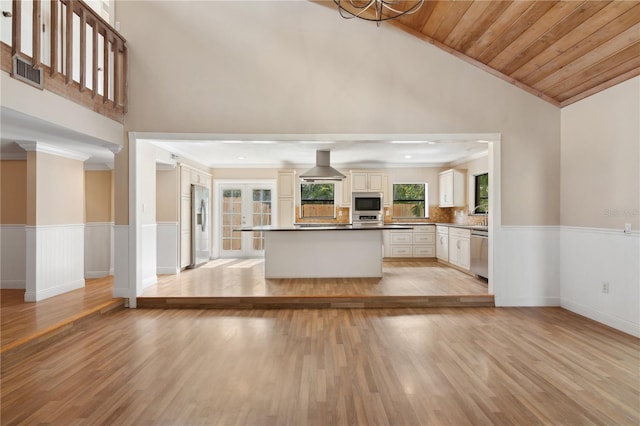 kitchen featuring appliances with stainless steel finishes, light wood-style flooring, a wainscoted wall, high vaulted ceiling, and ornamental molding