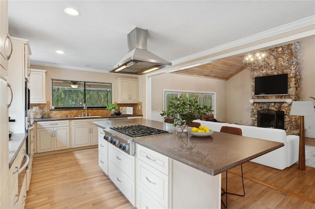 kitchen with stainless steel appliances, island range hood, a kitchen breakfast bar, light wood-style floors, and tasteful backsplash