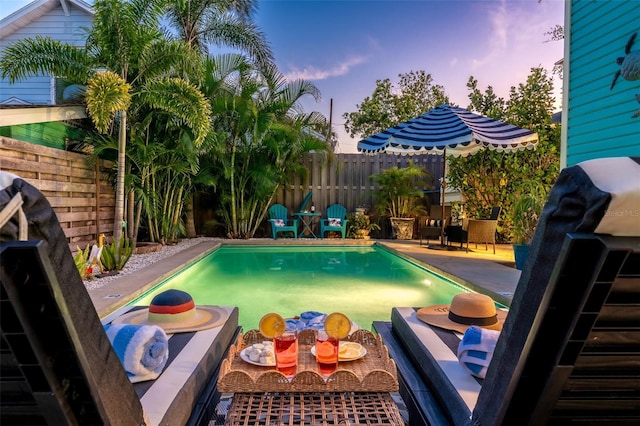 pool at dusk with a patio area