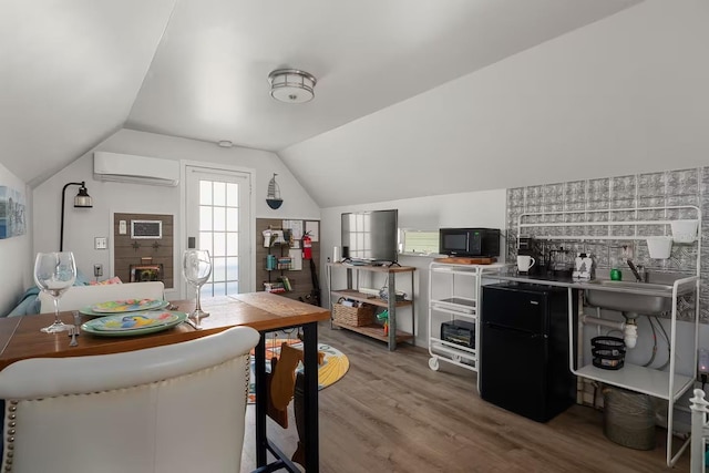 kitchen featuring lofted ceiling, sink, hardwood / wood-style flooring, and a wall unit AC