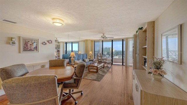 dining area featuring expansive windows, a textured ceiling, and light hardwood / wood-style floors