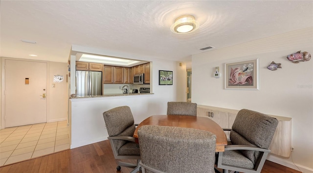 dining room with sink, a textured ceiling, and light wood-type flooring