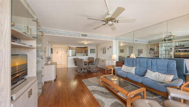 living room with dark wood-type flooring, ceiling fan, and a textured ceiling