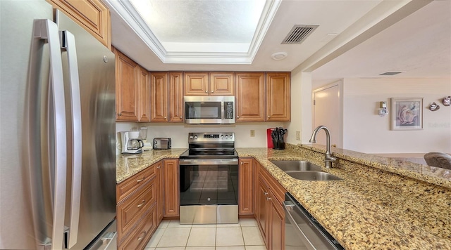 kitchen with appliances with stainless steel finishes, sink, light stone counters, and kitchen peninsula