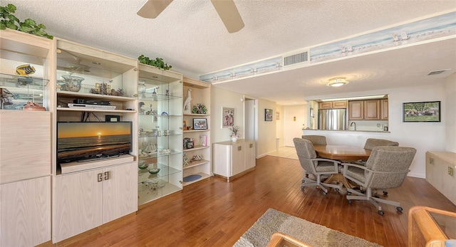 dining room with ceiling fan, wood-type flooring, sink, and a textured ceiling