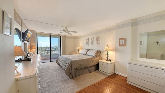 bedroom with hardwood / wood-style floors, a wall of windows, ceiling fan, and access to outside