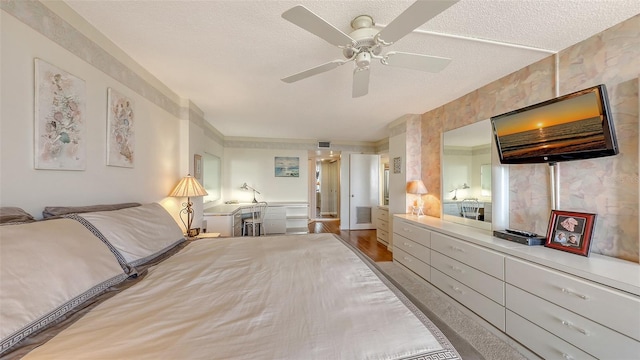 bedroom with ceiling fan, hardwood / wood-style floors, and a textured ceiling