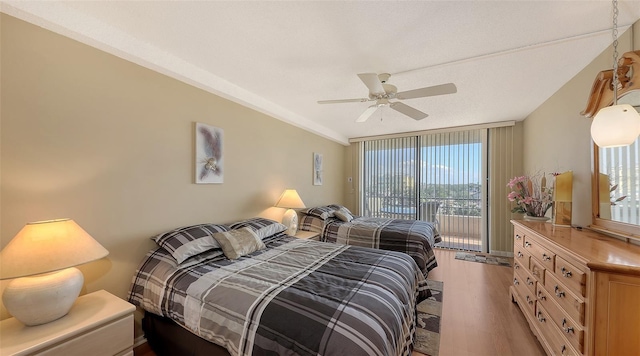 bedroom featuring ceiling fan, a wall of windows, wood-type flooring, and access to outside