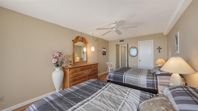 bedroom featuring ceiling fan, wood-type flooring, and a textured ceiling