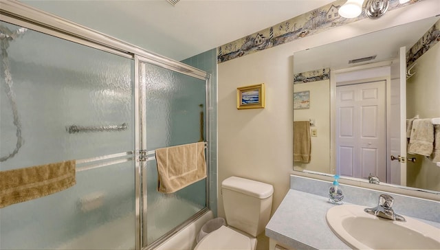 full bathroom featuring vanity, combined bath / shower with glass door, and toilet