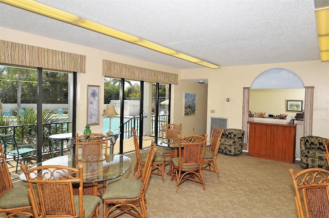 carpeted dining room featuring a textured ceiling