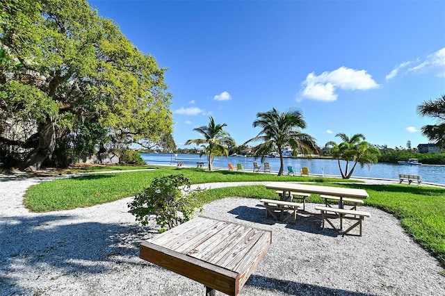 view of property's community with a yard, a patio, and a water view