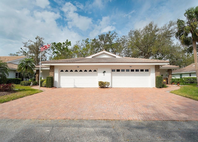 single story home featuring stucco siding, a tile roof, decorative driveway, and a garage