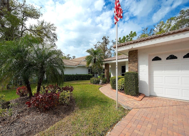 view of front of property featuring stucco siding, an attached garage, a tile roof, and a front lawn