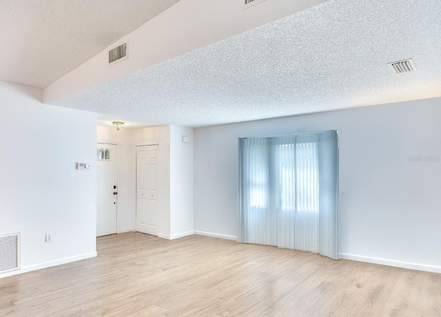 empty room with light wood-type flooring and visible vents