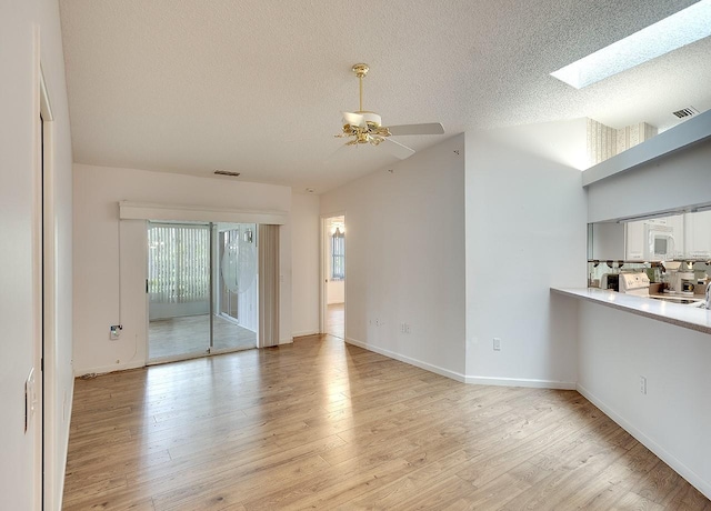 unfurnished living room featuring visible vents, light wood-type flooring, and a textured ceiling